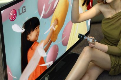 A female model points at the screen of LG's LW980S 3D LCD TV with 3D glasses in her hand.