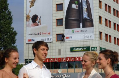 Visitors to IFA 2011 gather in front of a building displaying large advertisements for LG’s 3D products