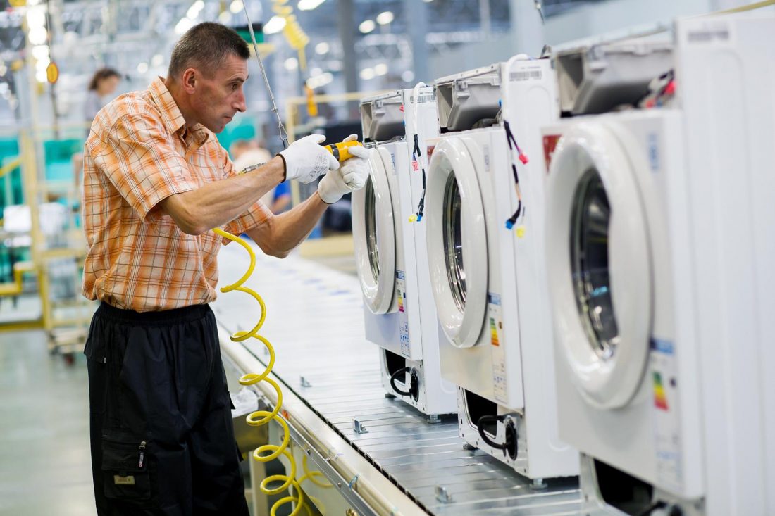 A staff member assembles washing machines on appliance production lines in Poland