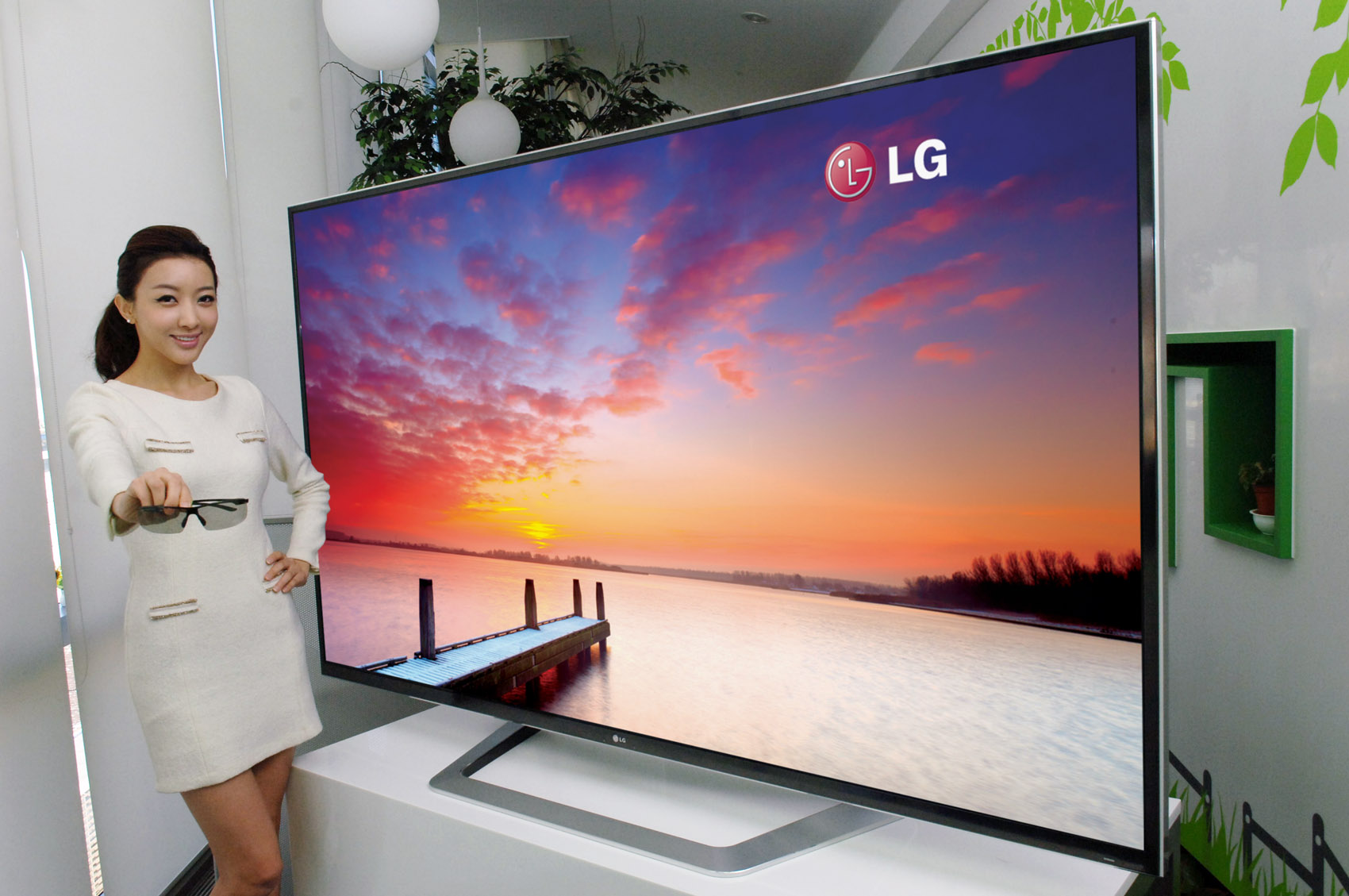 A model holding 3D glasses while showing off the world’s largest 84-inch 3D Ultra Definition TV