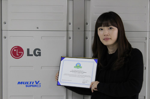 A wider shot of a woman holding up LG MULTI V III’s carbon-free certification letter in front of the air conditioner appliance.