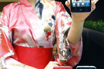 A woman in traditional Japanese clothing holds up LG Optimus LTE and shows its front view, while two LG Optimus LTEs displaying its front and back are displayed in front of her