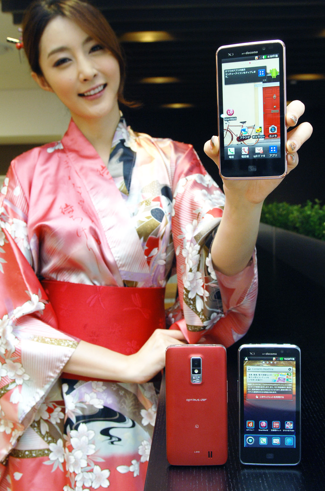 A woman in traditional Japanese clothing holds up LG Optimus LTE and shows its front view, while two LG Optimus LTEs displaying its front and back are displayed in front of her