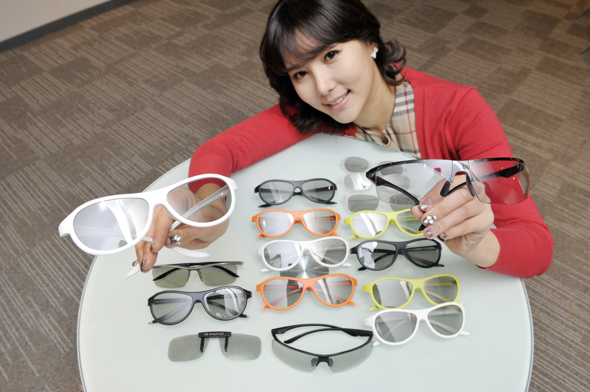 A model presenting the various types and colors of LG’s new 3D glasses lineup on a table