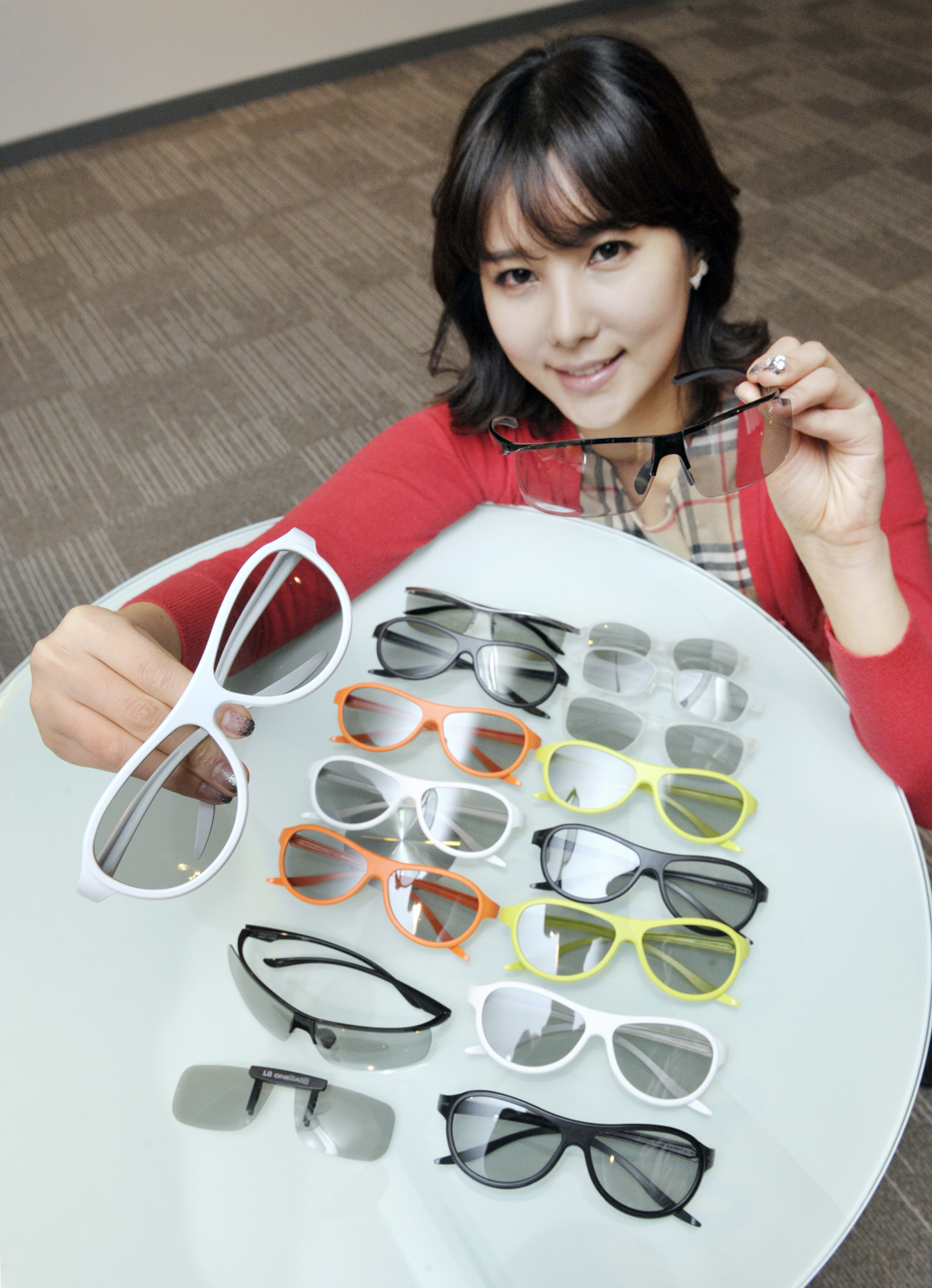 A model presenting the various types and colors of LG’s new 3D glasses lineup on a table