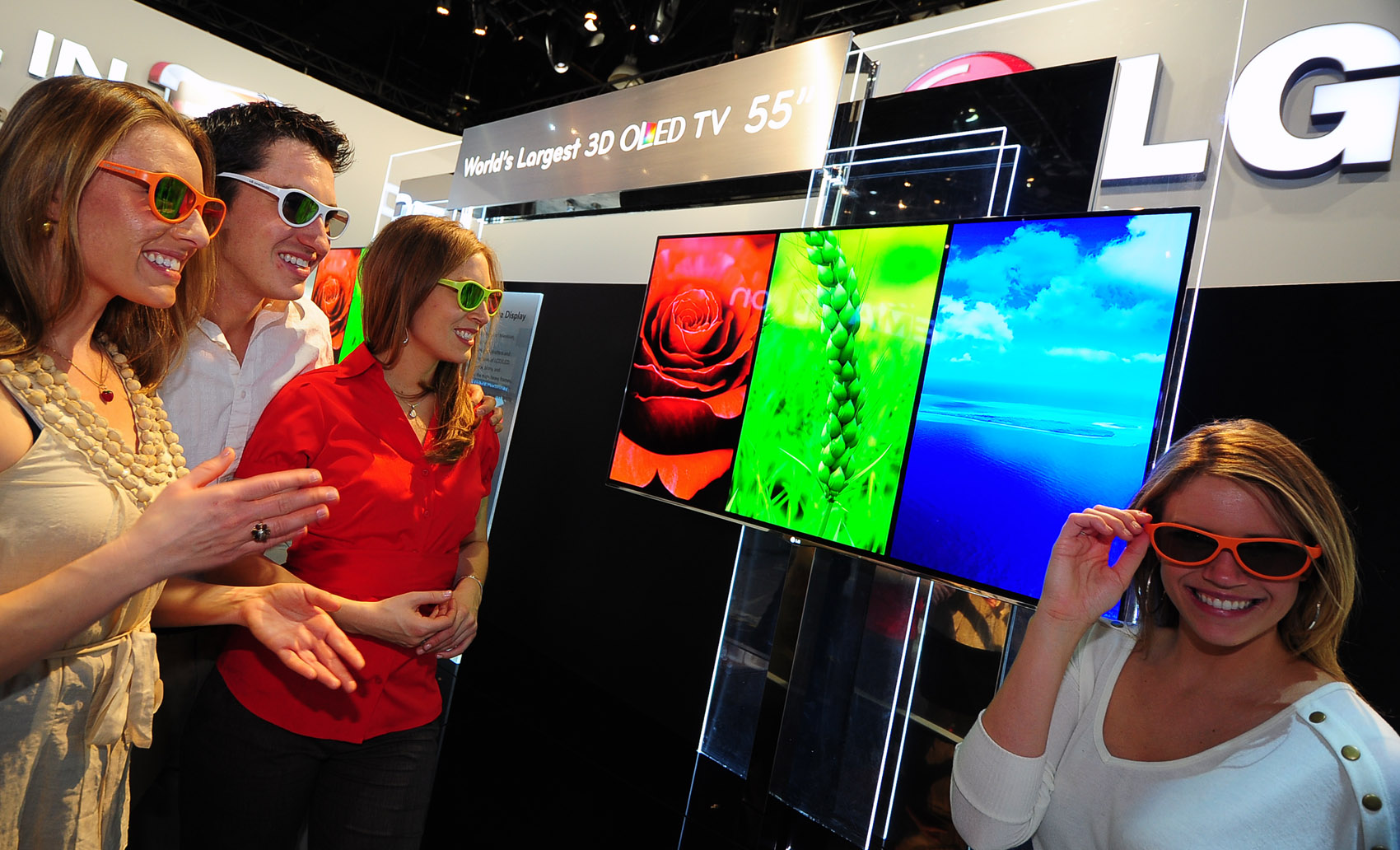 Three visitors and a model wearing 3D glasses to experience LG’s 3D TVs at CES 2012