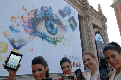 4 female models hold LG Optimus Vu:, LG Optimus 4X HD, LG Optimus 3D Max and LG Optimus L7 and show its front and rear views in front of the main entrance of Fira de Barcelona, Montjuïc venue