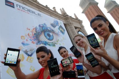4 female models hold LG Optimus Vu:, LG Optimus 4X HD, LG Optimus 3D Max and LG Optimus L7 and show its front and rear views in front of the main entrance of Fira de Barcelona, Montjuïc venue