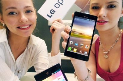 Two models holding up two LG QUAD-CORE smartphones and a promotional panel engraved with the brand name LG OPTMUS 4X HD