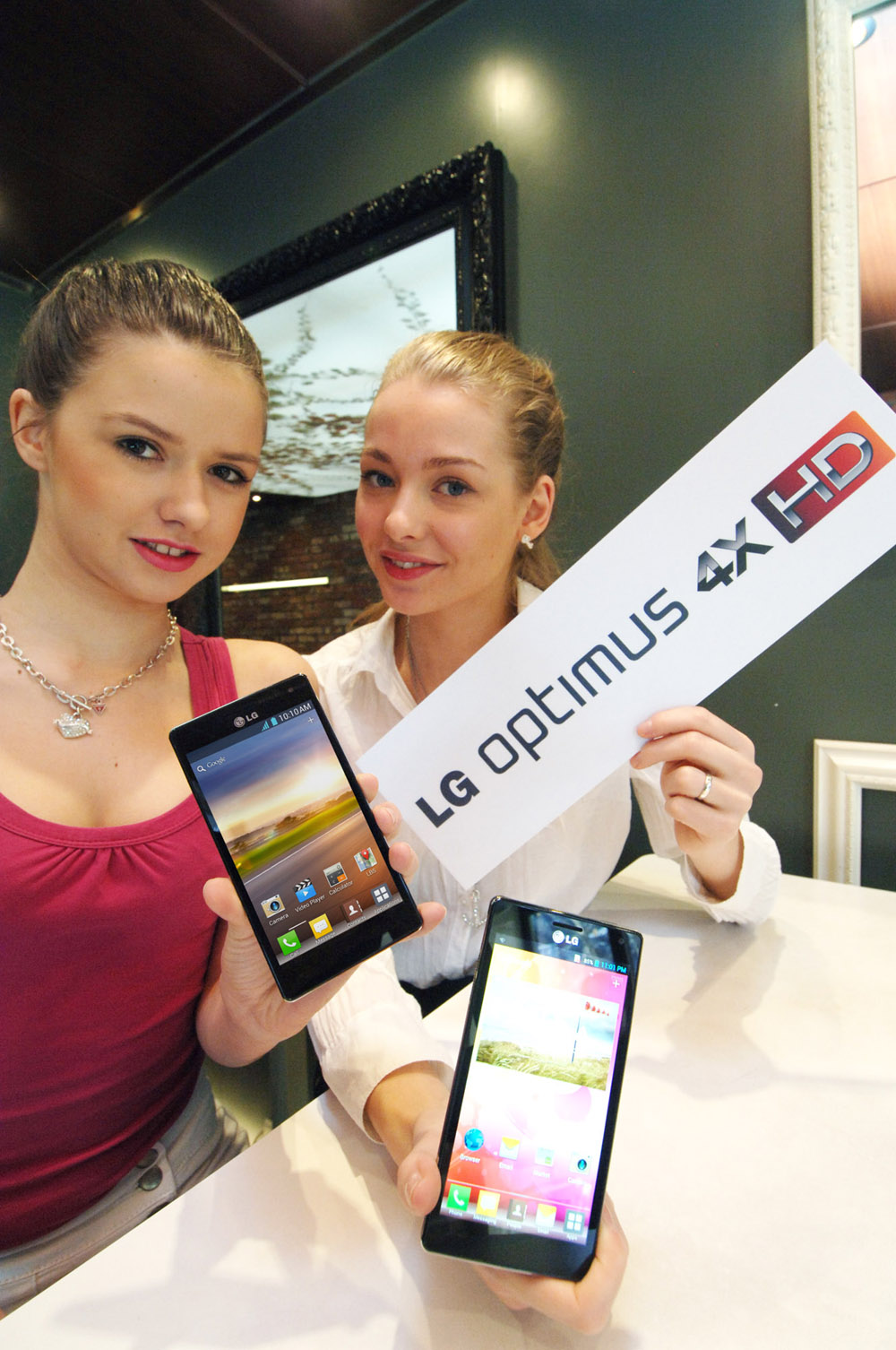 Another photo of two models holding up two LG QUAD-CORE smartphones and a promotional panel engraved with the brand name LG OPTMUS 4X HD