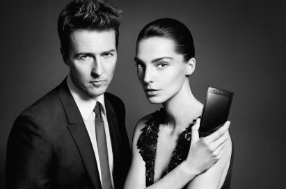 Daria Werbowy holds up the PRADA phone by LG 3.0 showing its front with Edward Norton