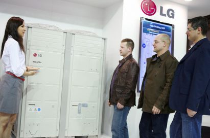 A female attendant explains LG’s Multi V HVAC solution to three men at MCE 2012.