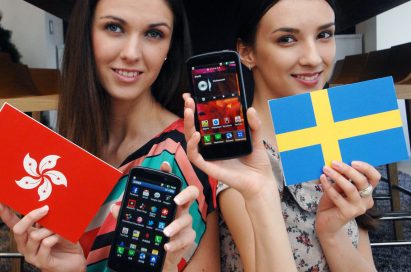 A different view of a model holding a Hong Kong flag and the LG Optimus HD LTE while another holds up the flag of Sweden and another LG Optimus HD LTE, all while in front of the Germany, Portugal and Singapore flags