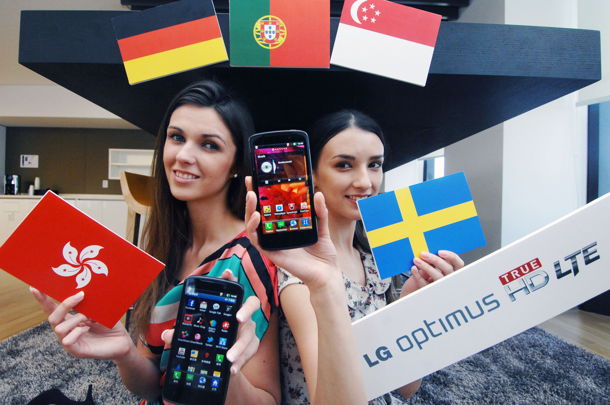 A model holding a Hong Kong flag and the LG Optimus HD LTE while another holds up the flag of Sweden and another LG Optimus HD LTE, all while in front of the Germany, Portugal and Singapore flags