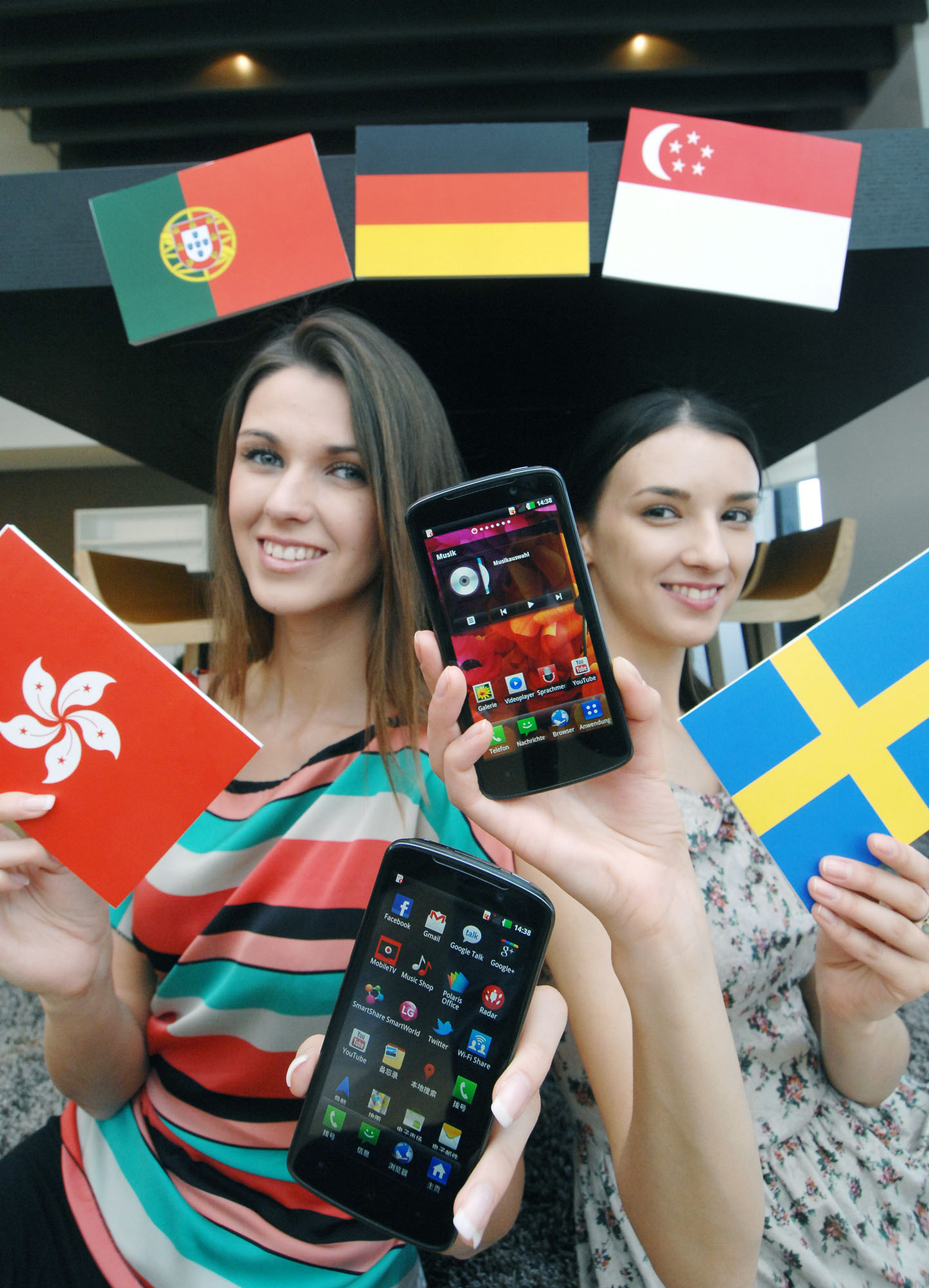 A third view of a model holding a Hong Kong flag and the LG Optimus HD LTE while another holds up the flag of Sweden and another LG Optimus HD LTE, all while in front of the Germany, Portugal and Singapore flags