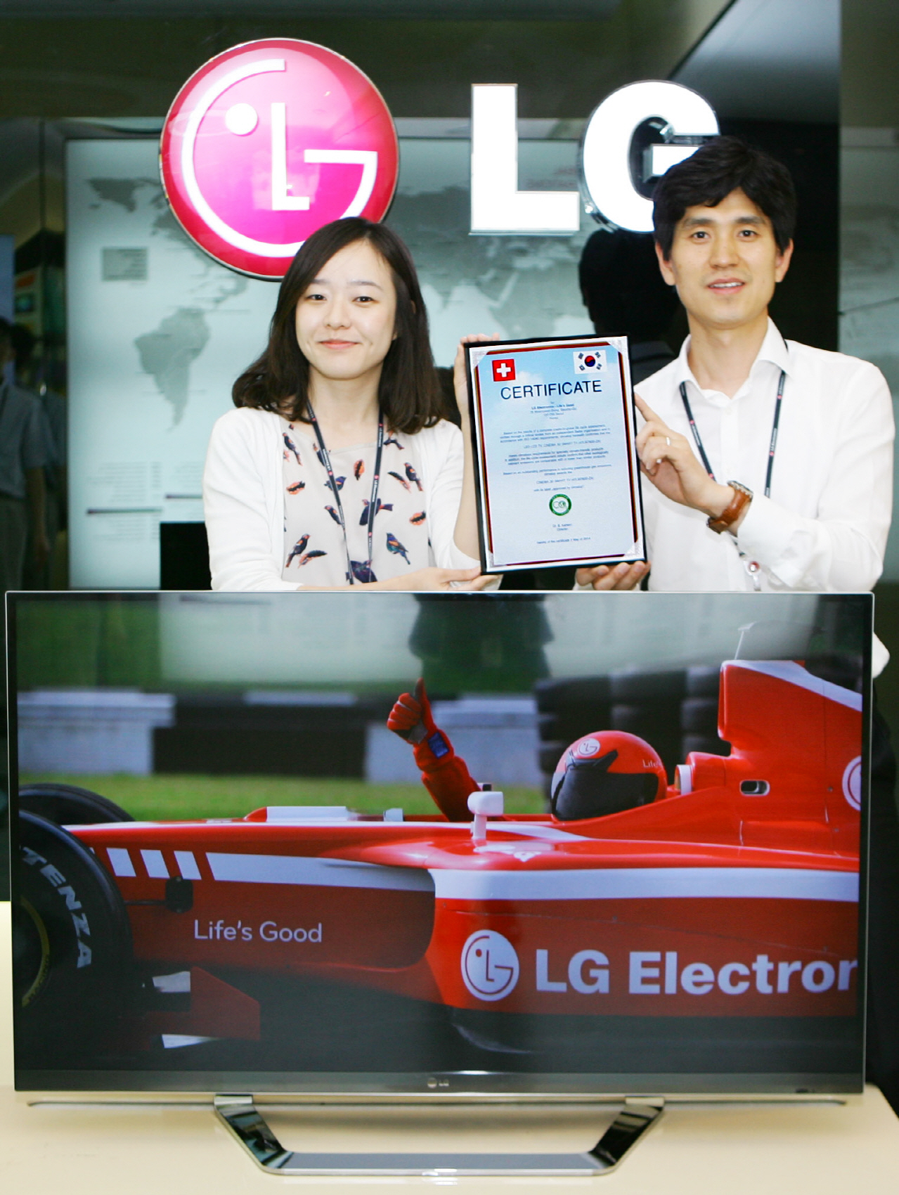 Two LG employees hold up the Climatop certificate behind the company’s CINEMA 3D Smart TV model 47LM760S
