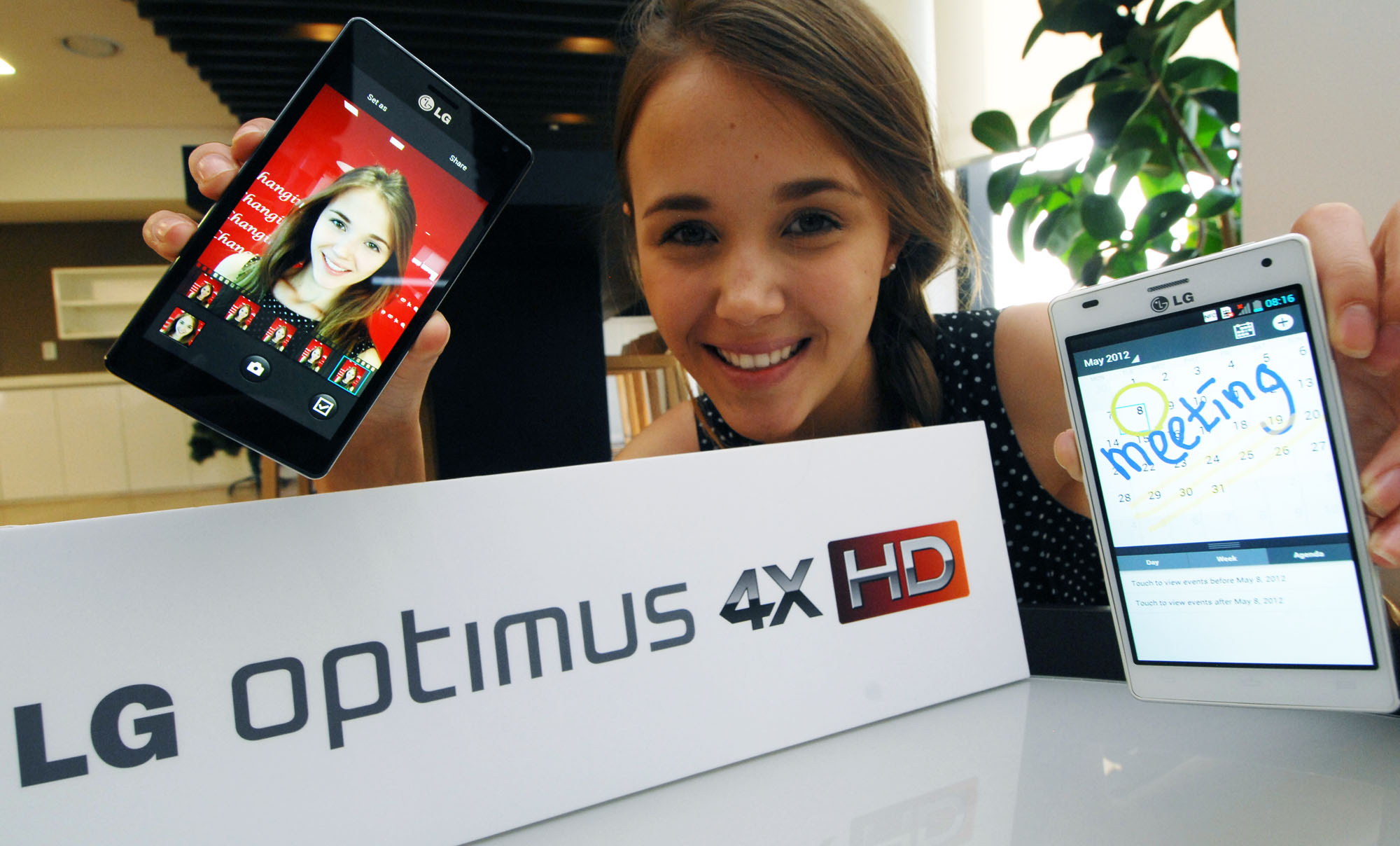 A model holds a black and white versions of LG Optimus 4X HD behind the logo of LG Optimus 4X HD