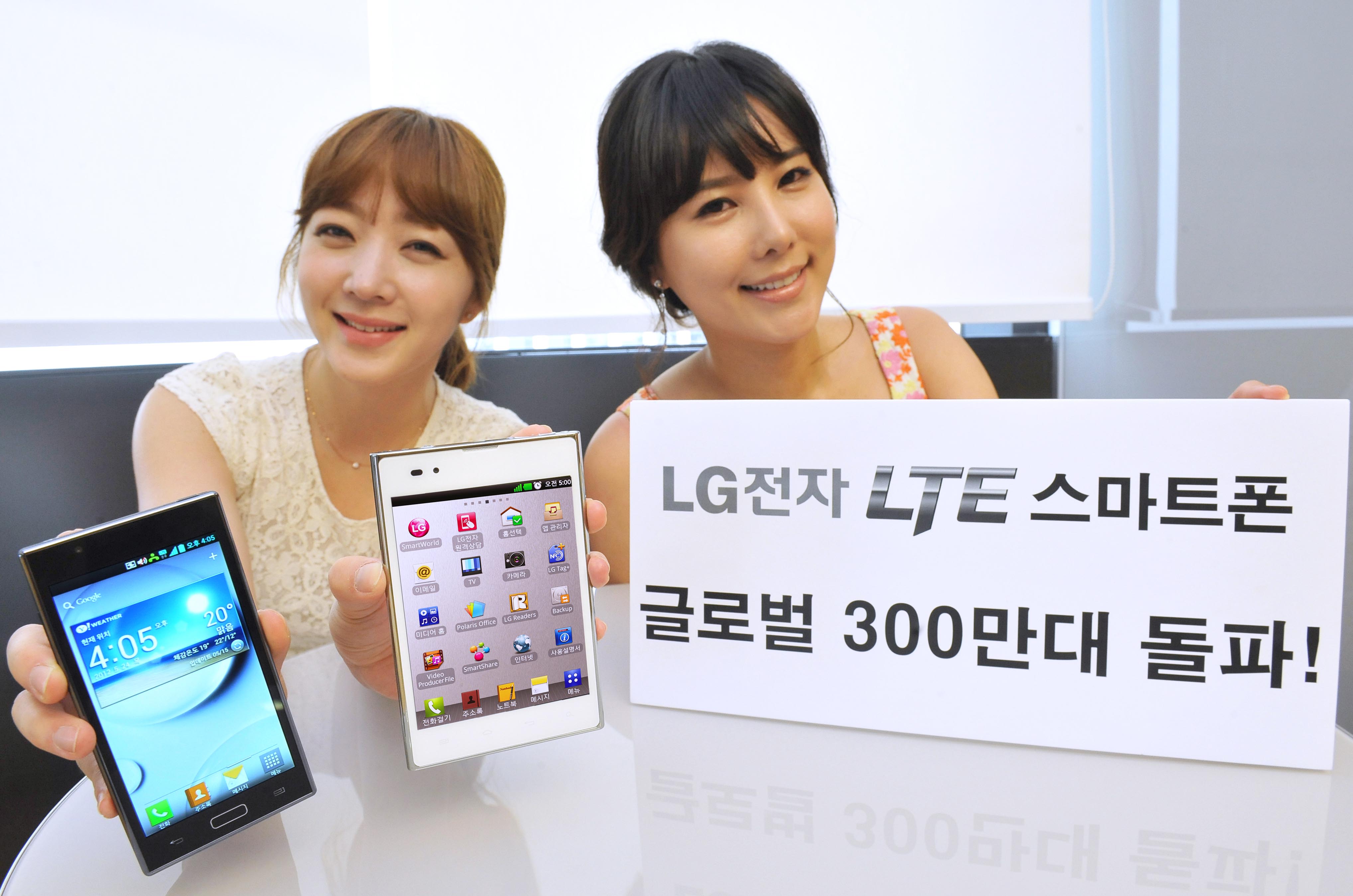 A model holds the black LG Optimus LTE in one hand and the white version in the other, while another model holds a paper panel celebrating three million sales