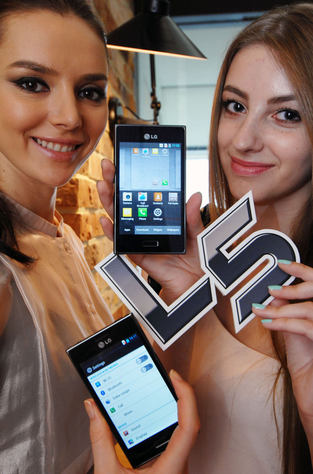 Close view of two women holding two LG OPTIMIUS L5s between them