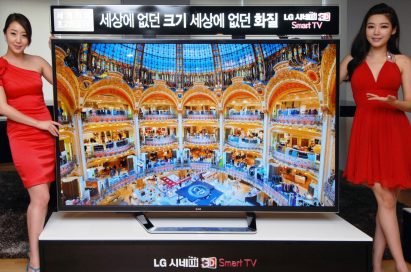 Two models posing at either side of the world’s first 84-inch Ultra Definition 3D TV by LG