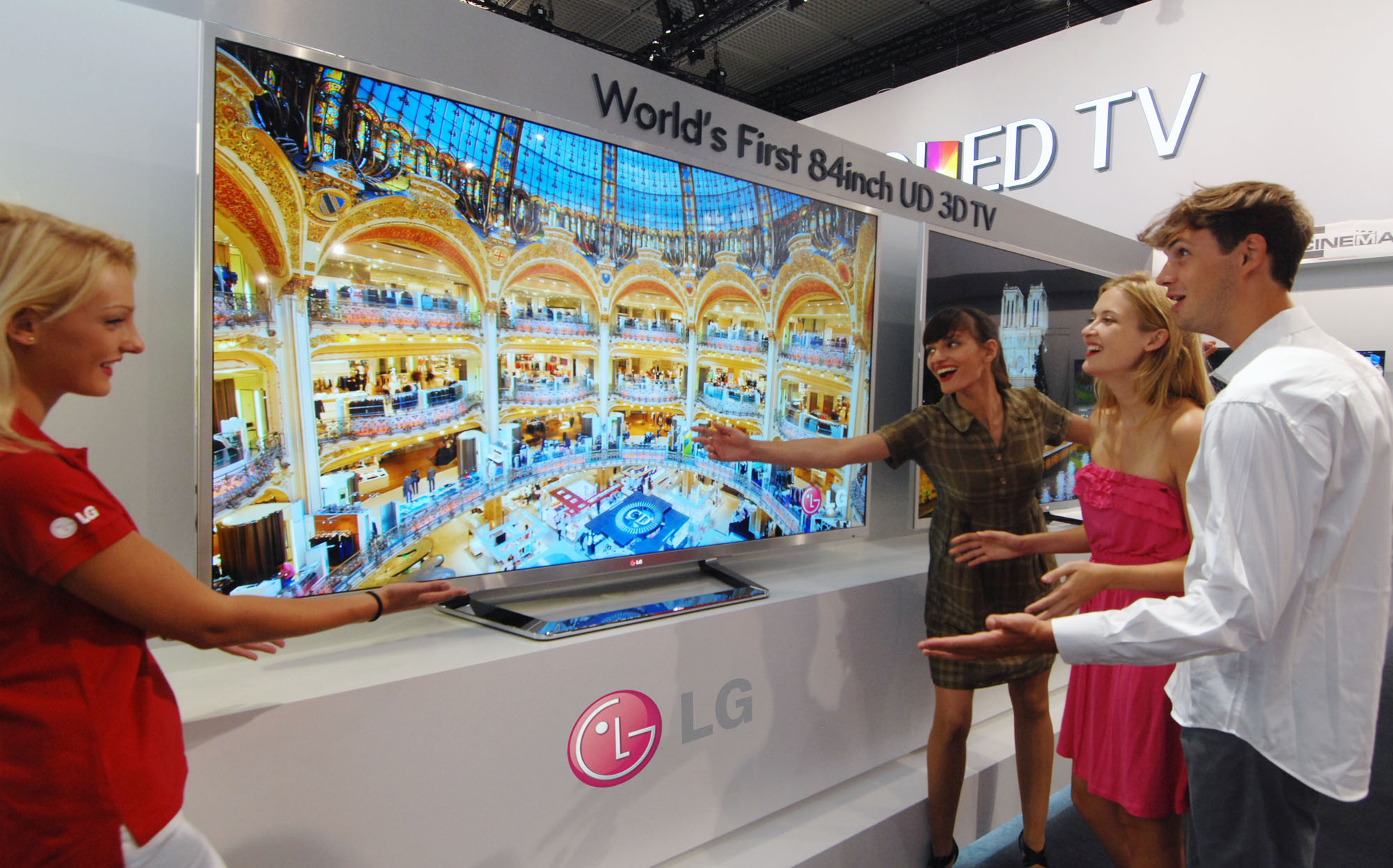 An LG booth staff member introducing the world’s first 84-inch UD 3D TV to visitors at IFA 2012