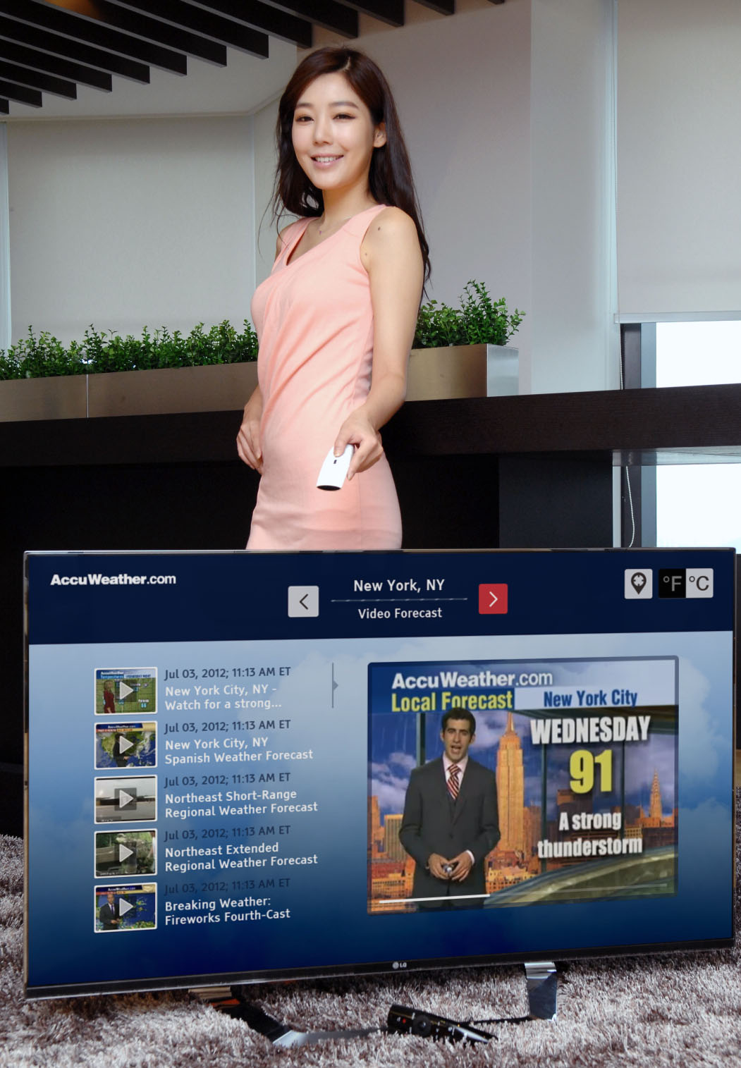 A model controlling an LG Smart TV as it displays a weather forecast channel