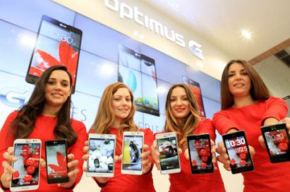 Four female models are smiling at a camera holding various strategic Optimus series devices at MWC 2013 - G, Vu:, F and LII.