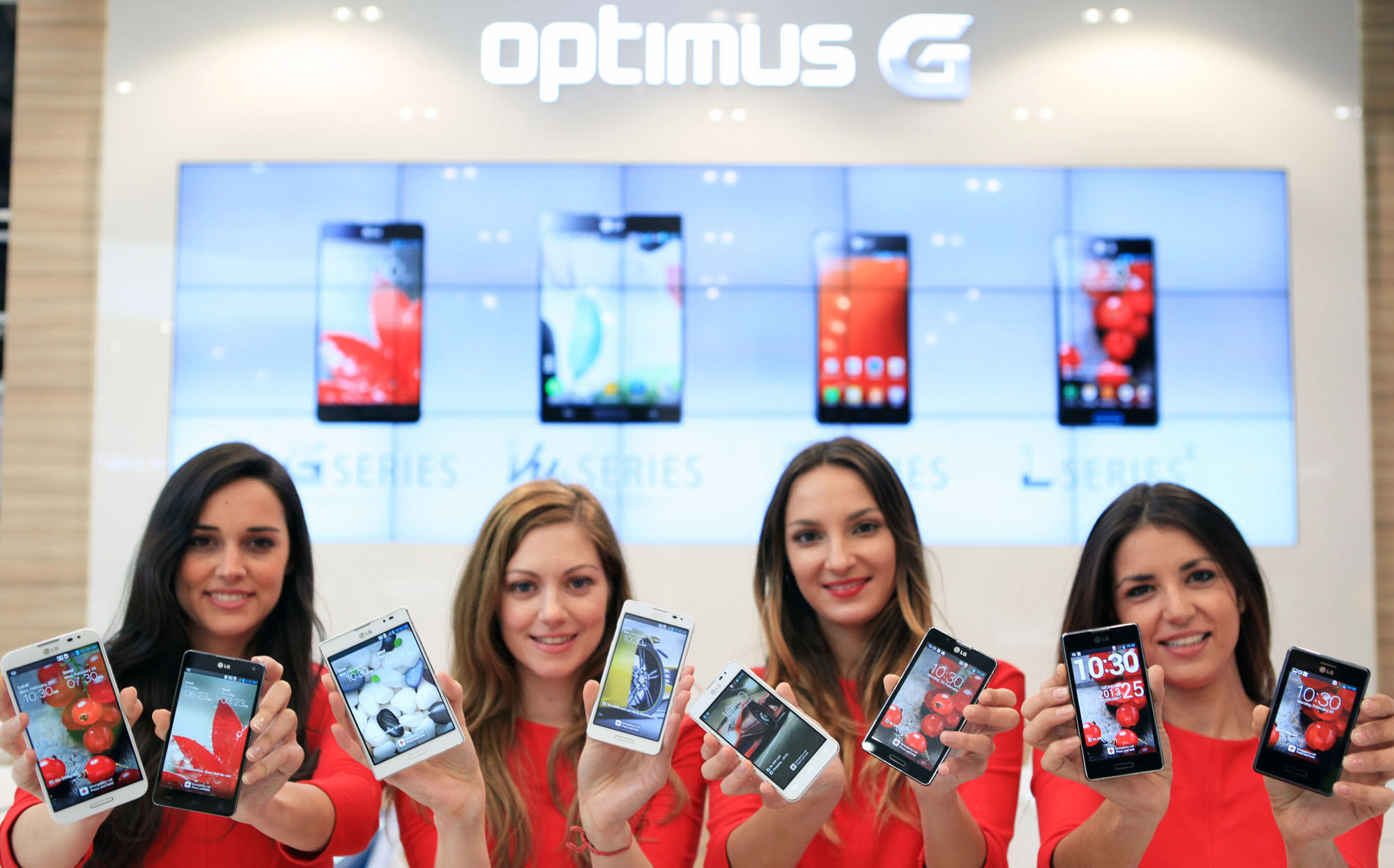 Four female models are smiling at a camera holding various strategic Optimus series devices at MWC 2013 - G, Vu:, F and LII.