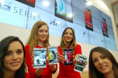 Four female models are smiling at a camera holding various strategic Optimus series devices at MWC 2013 - G, Vu:, F and LII.