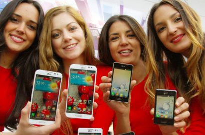 Four female models are smiling at a camera holding various strategic Optimus series devices at MWC 2013 - G, Vu:, F and LII.