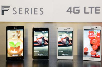 Four of new LG Optimus F series smartphones are displayed. From left to right; Optimus F7 in black color, Optimus F5 in black color, Optimus F5 in white color, Optimus F7 in white color. A panel saying “F SERIES 4G LTE” is also attached to the wall behind the handsets.