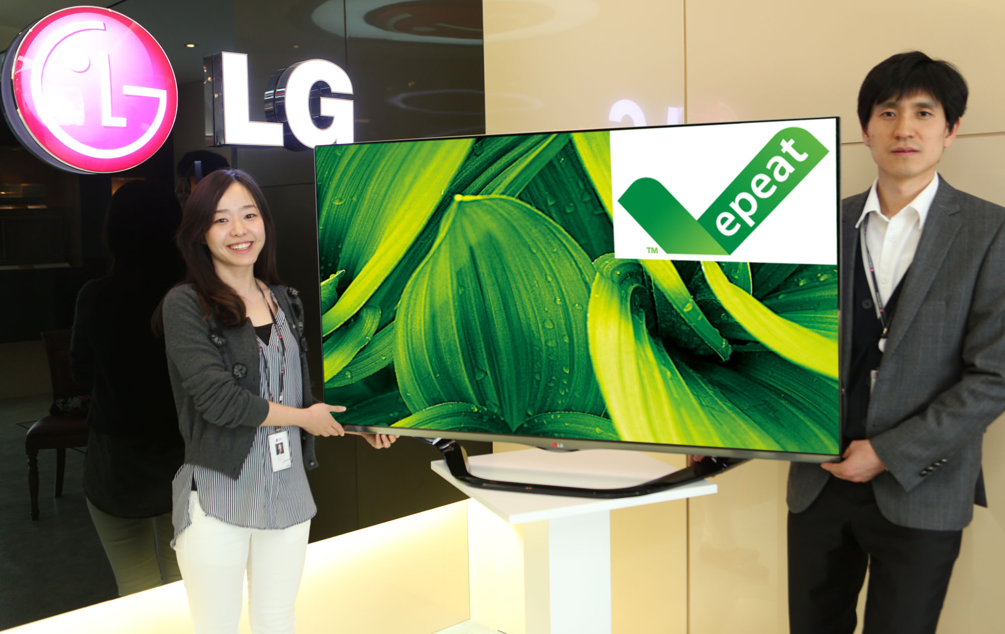 Two LG employees holding up an LG TV displaying the EPEAT logo