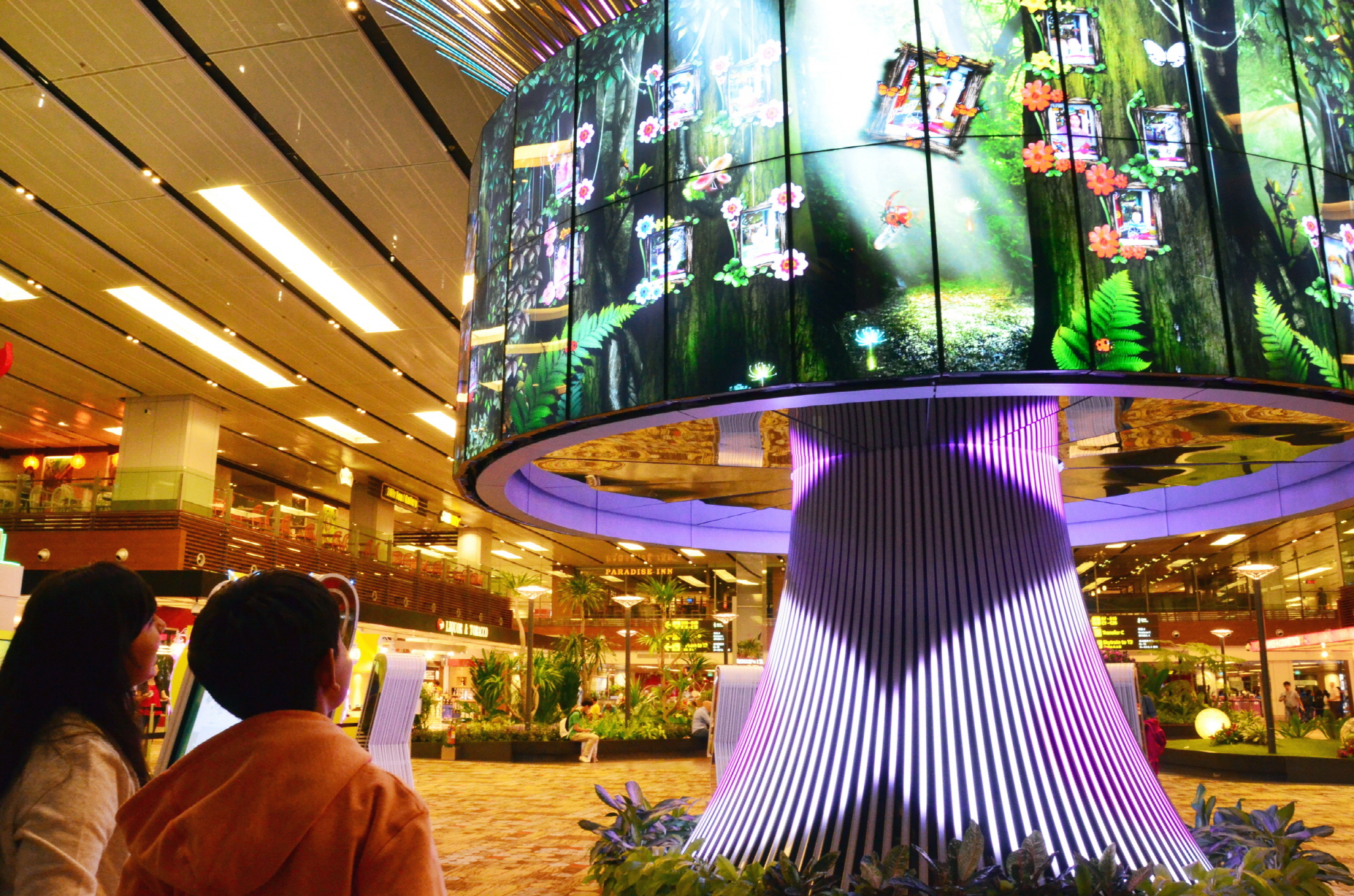 Travelers watch the vivid imagery of LG’s 64 47WV30 displays within the Social Tree installation at Changi Airport’s Terminal One