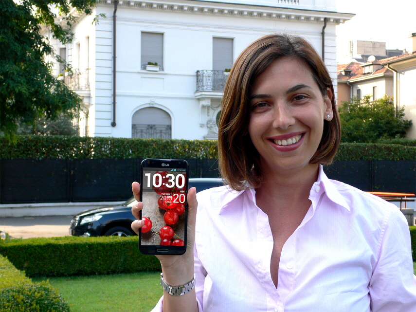 A woman posing in a garden holding the LG Optimus G Pro.