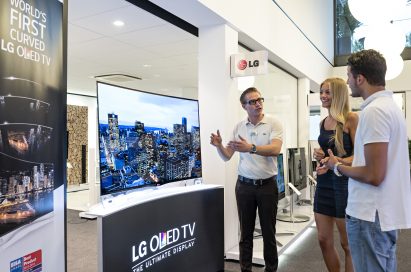 A member of staff explaining the LG CURVED OLED TV model 55EA9800 to visitors