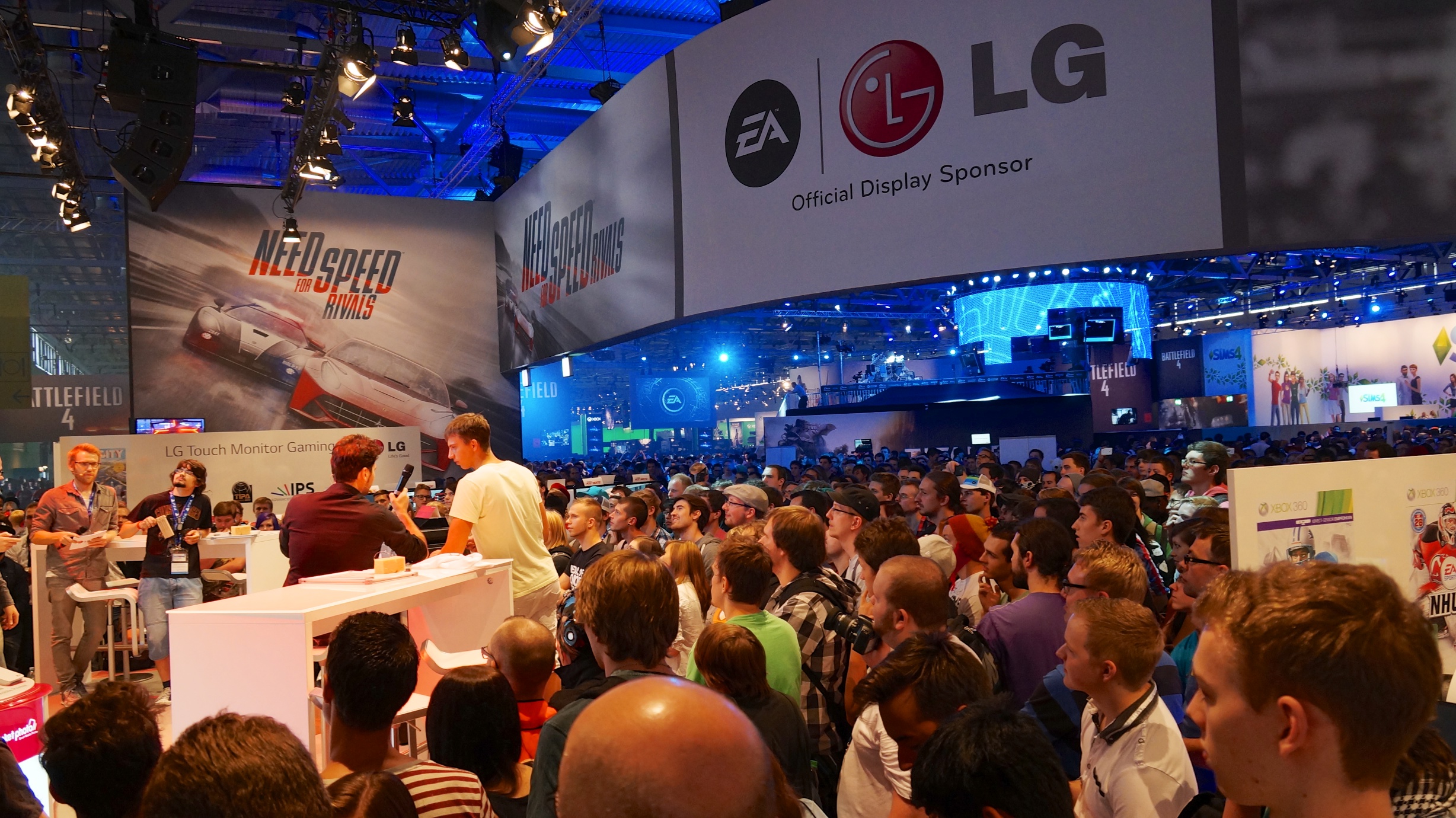 Staff at LG and EA’s stage interview a visitor while others watch on at Gamescom 2013