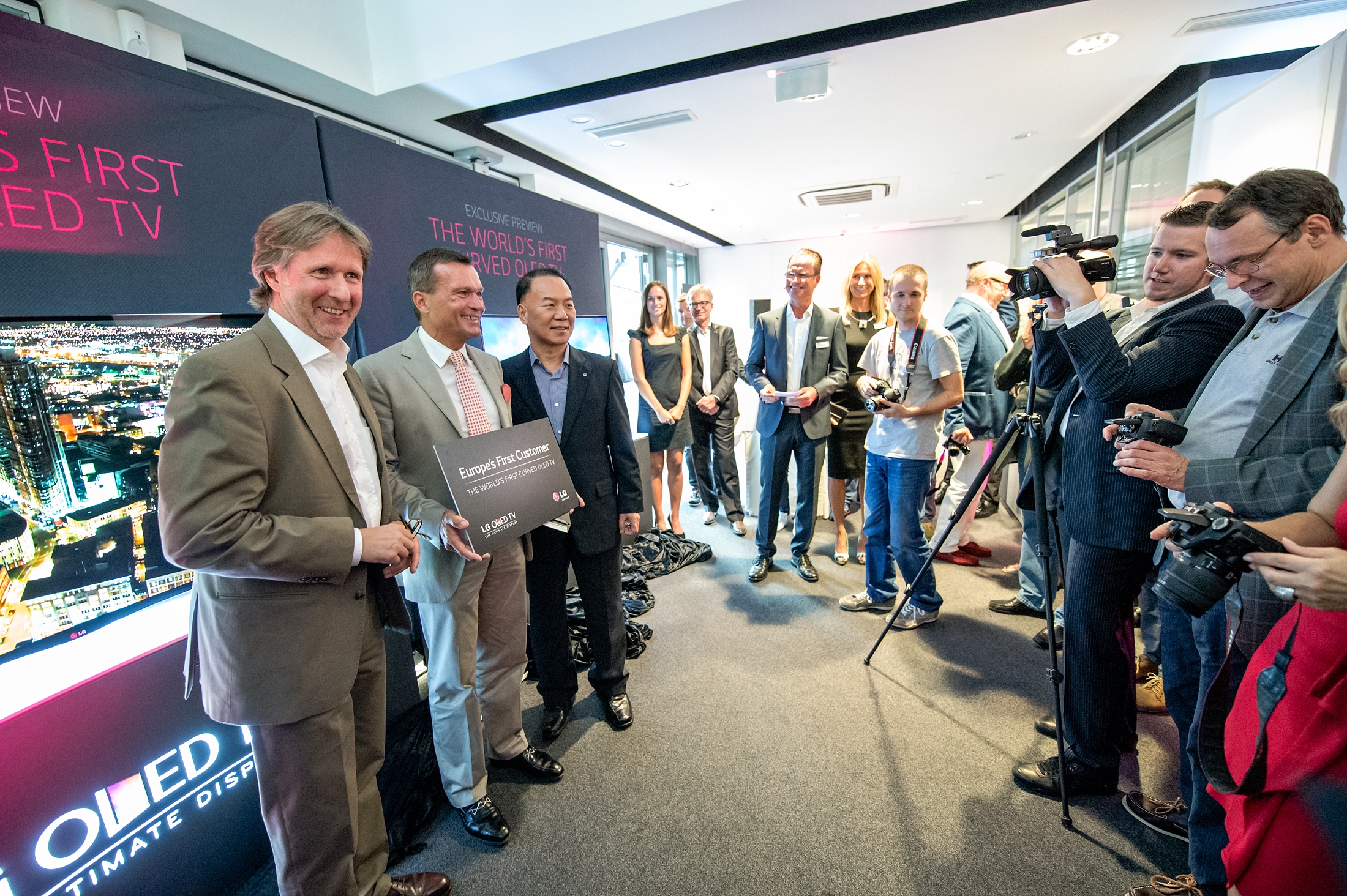 An LG representative and two German market representatives posing for the camera at the exclusive preview of the world’s first curved OLED TV.