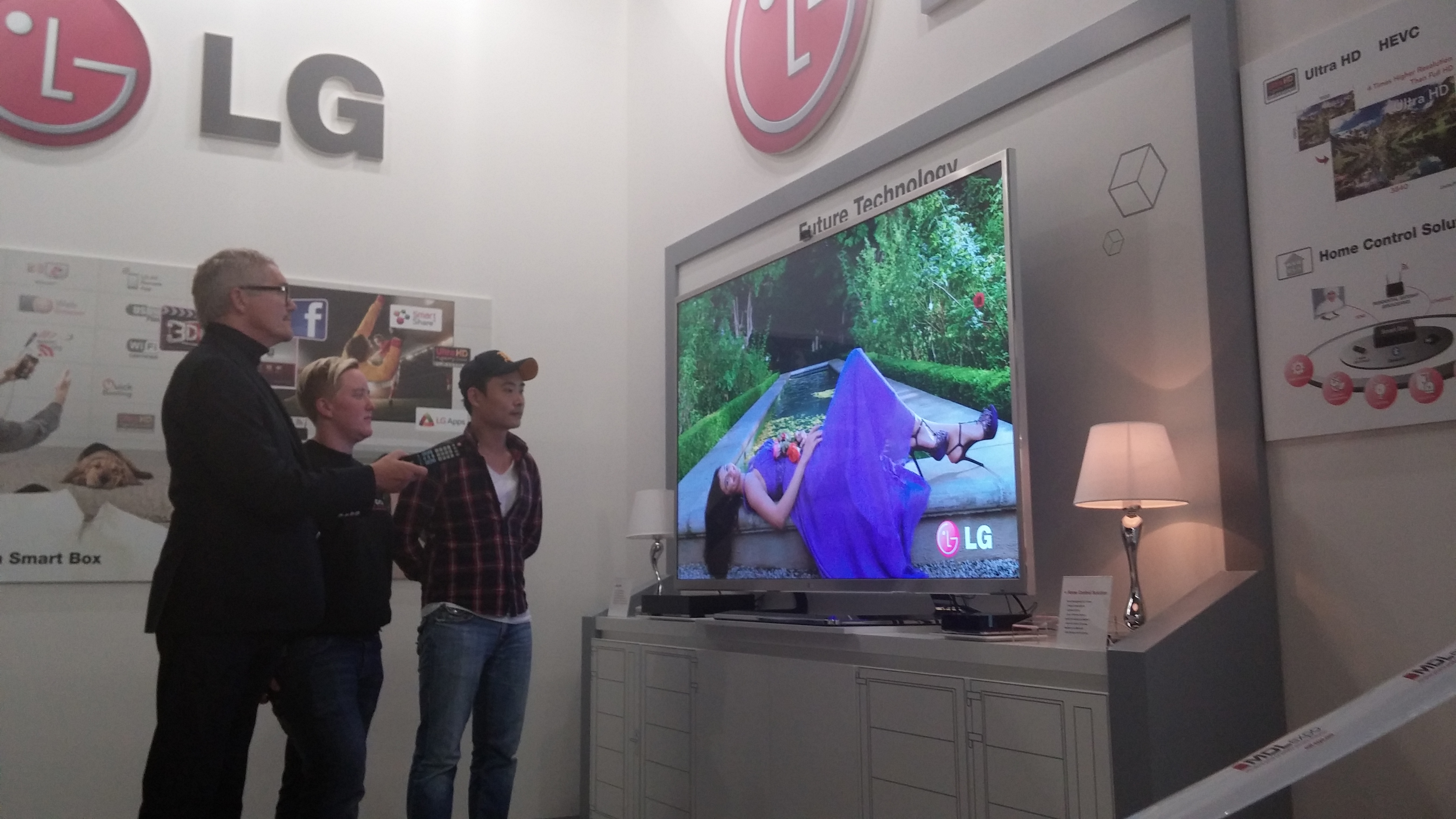 Three visitors watching LG’s comprehensive lineup of set-top boxes in LG’s International Broadcasting Convention booth