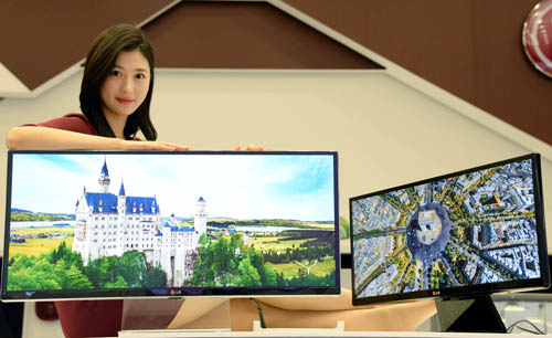 A model presenting the 34-inch and 29-inch IPS 21:9 UltraWide monitors while leaning on the 34-inch model.