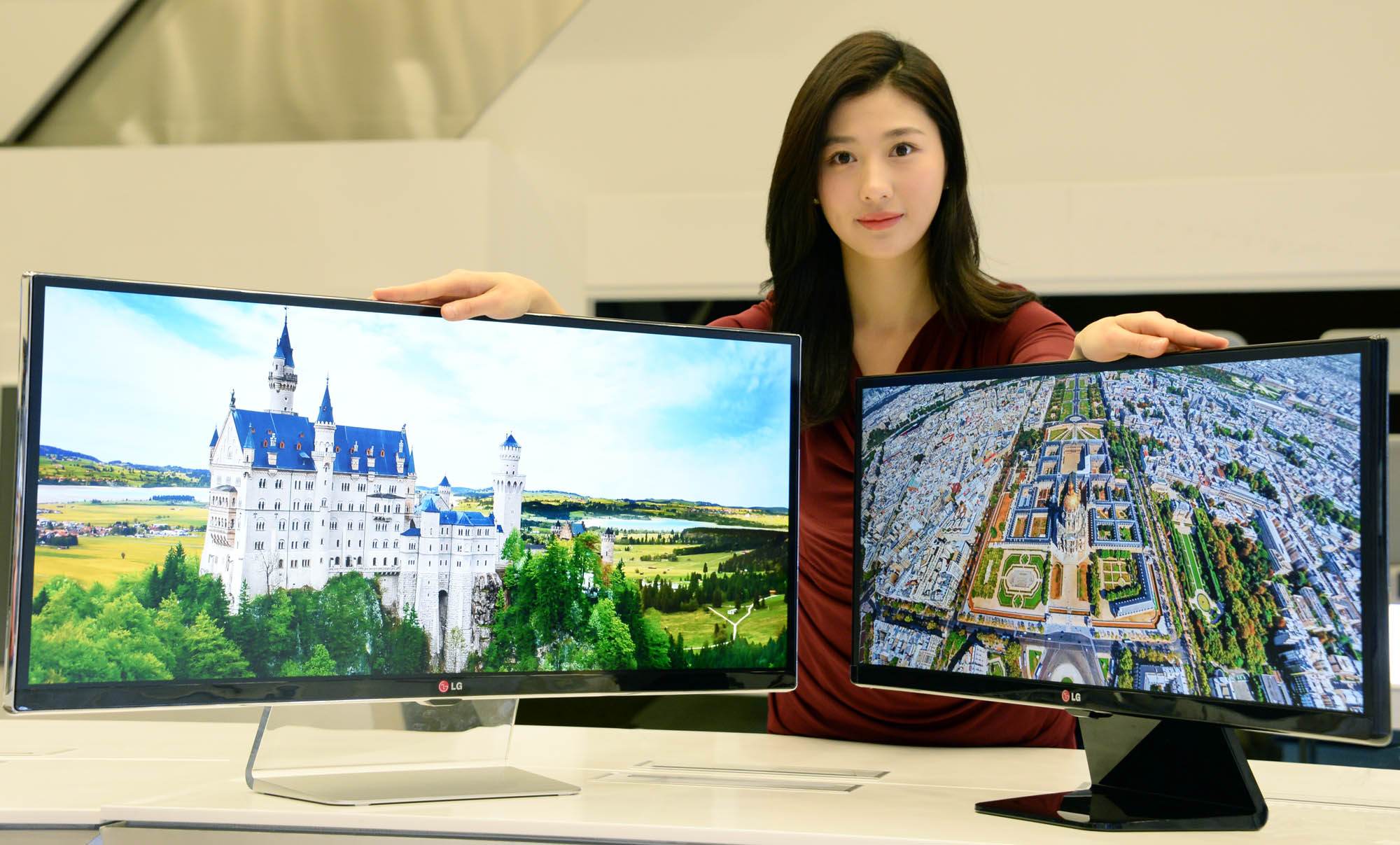 A model presenting 34-inch and 29-inch IPS 21:9 UltraWide monitors while putting her hands on both