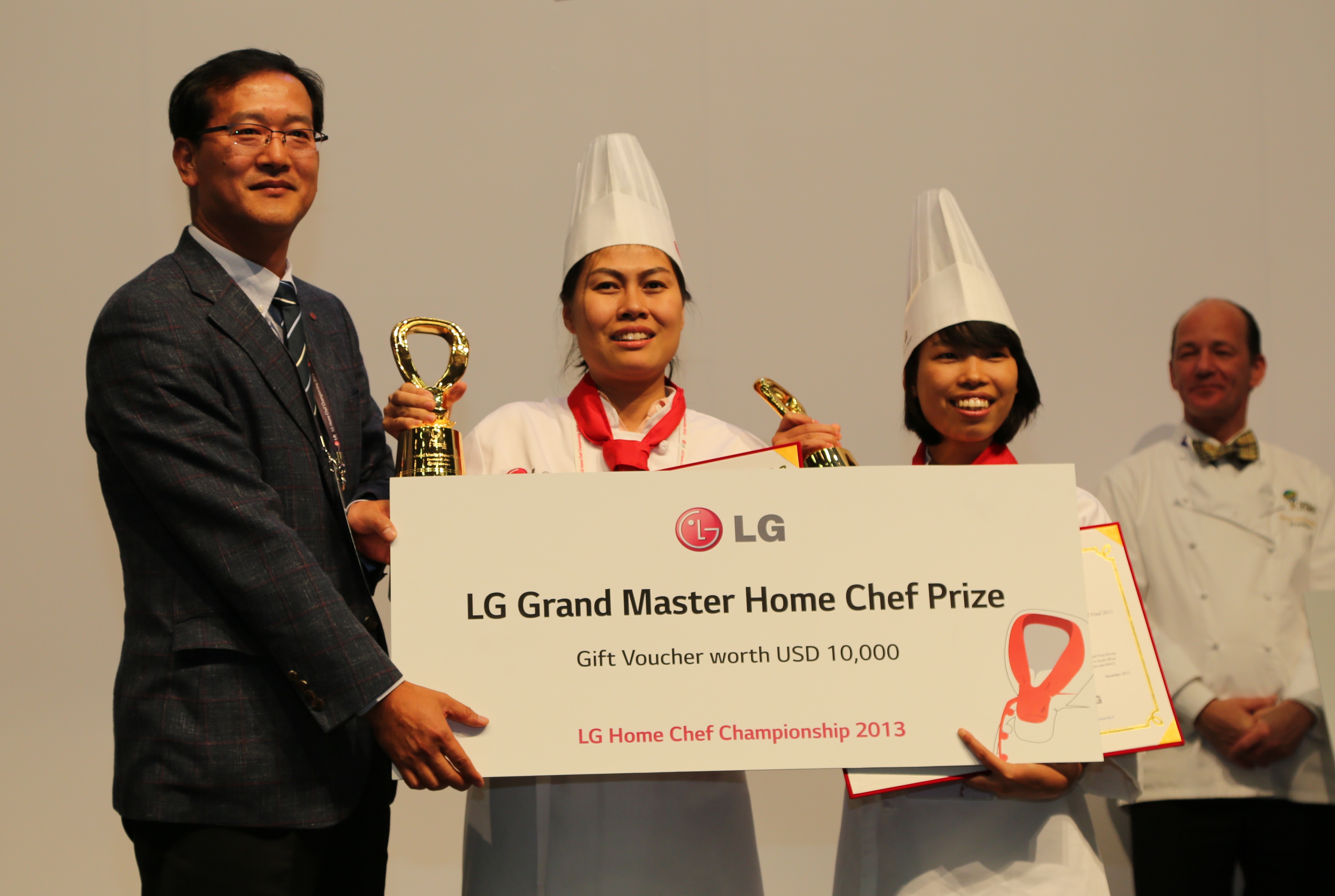 An LG representative awards the winners of the LG Grand Master Home Chef Prize with a gift voucher of USD $10,000 at the LG Home Chef Championship 2013