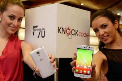 From left to right; A female model is holding a LG F70 in white color to show its back and another model is trying to show its front.
