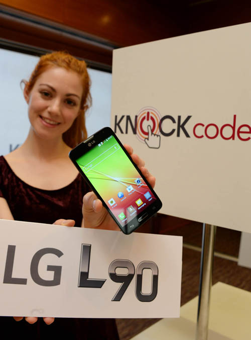 A female model is holding a LG L90 in her left hand and a panel with the logo of LG L90 on with her right hand.