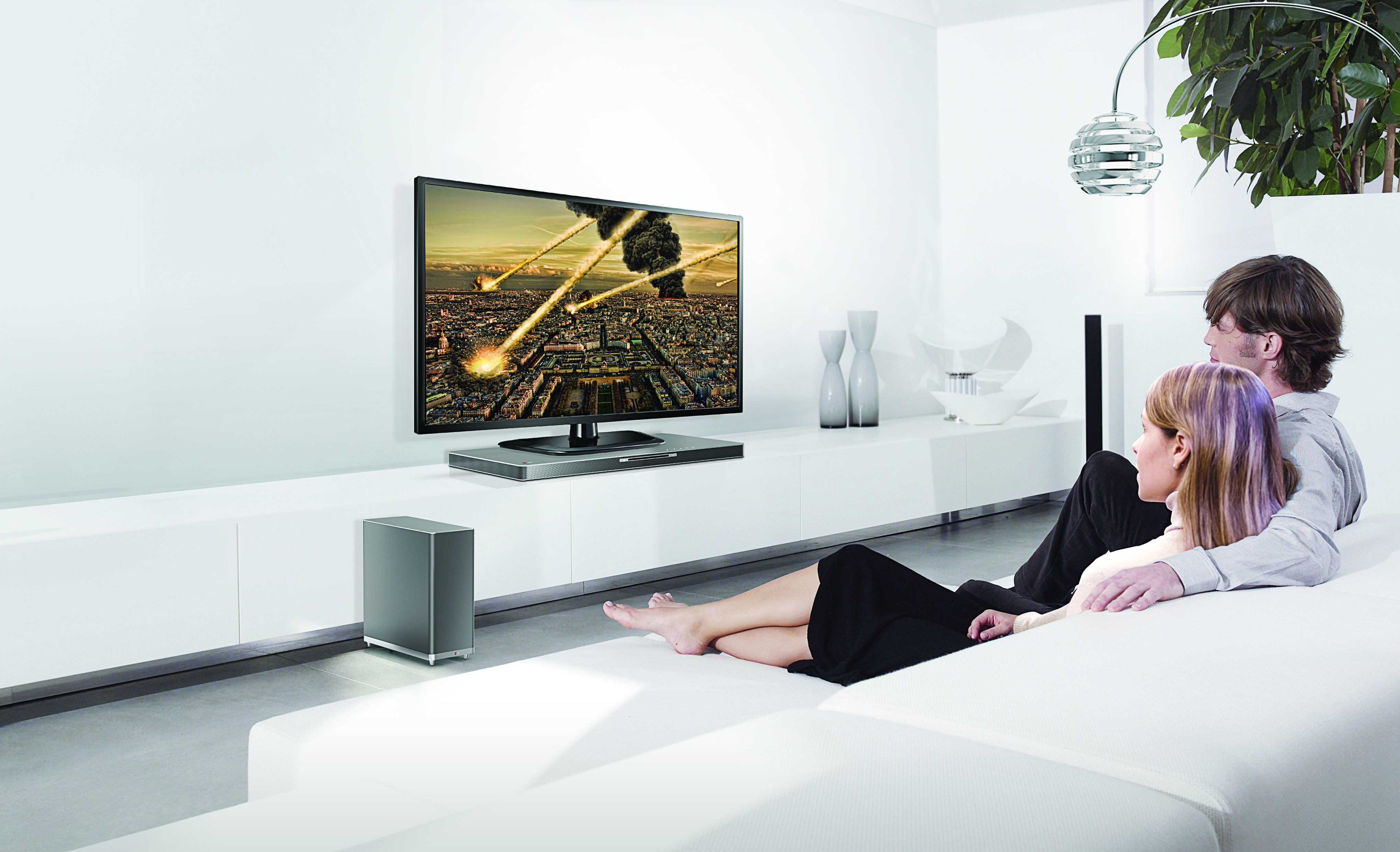 Two models watching TV on the LG SoundPlate model LAB540 while enjoying an impressive sound experience