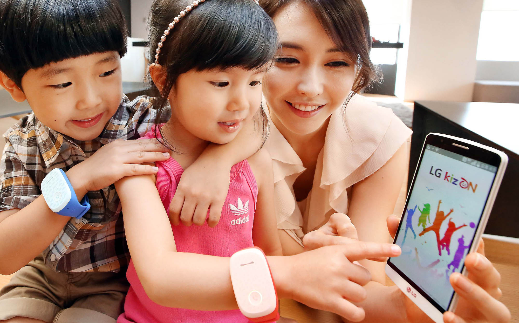 Two kid models wearing LG KizONS and a female model are trying to link the handsets with LG G3