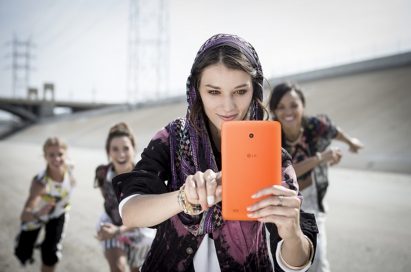 A woman and 3 kids are taking selfies with a LG G Pad 8.0 LTE.