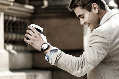 A man wearing a LG G Watch R is holding a cup of coffee.