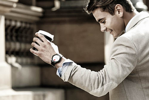 A man wearing a LG G Watch R is holding a cup of coffee.