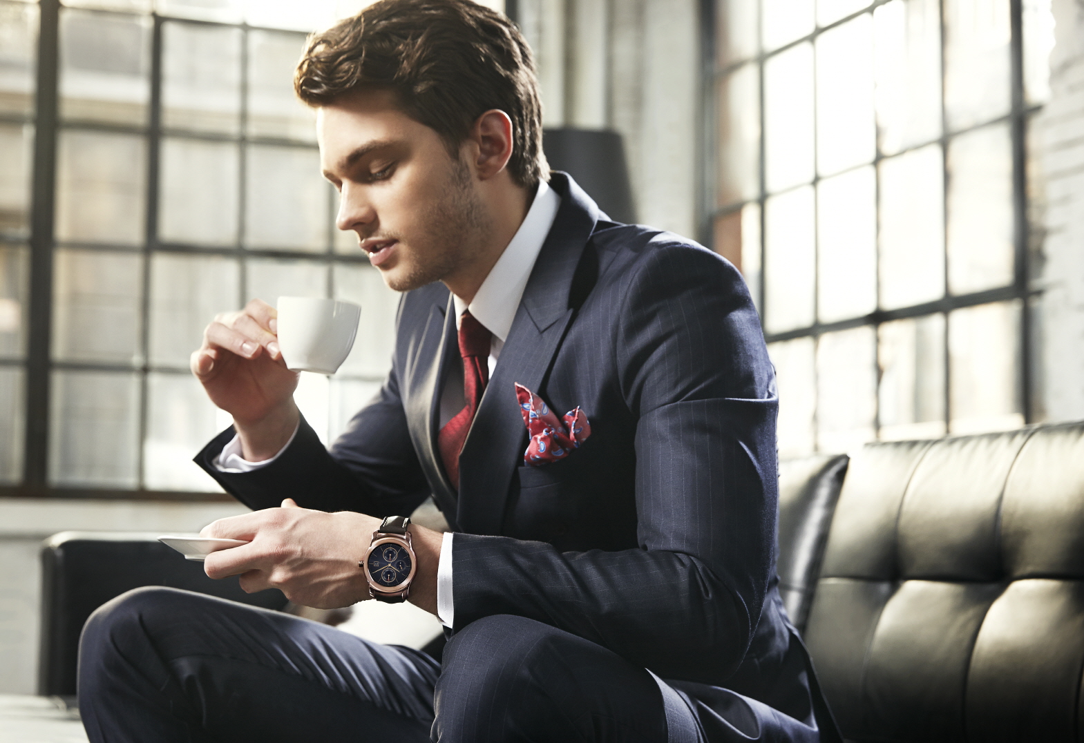 A man is holding up a cup of coffee wearing LG Watch Urbane in gold color.