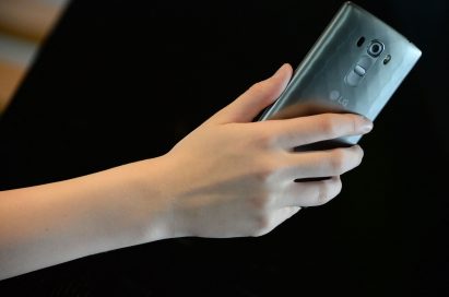 A close-up of a woman holding the LG G4 Beat in Metallic Silver color, showing its rear side.